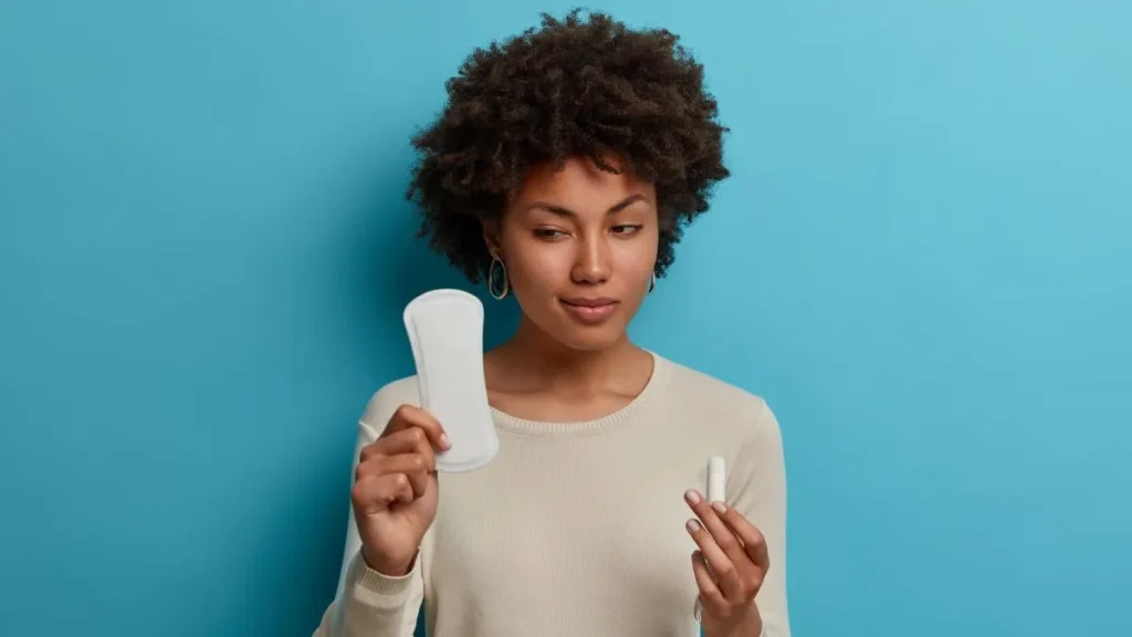 Donna dubbiosa che guarda assorbente femminile